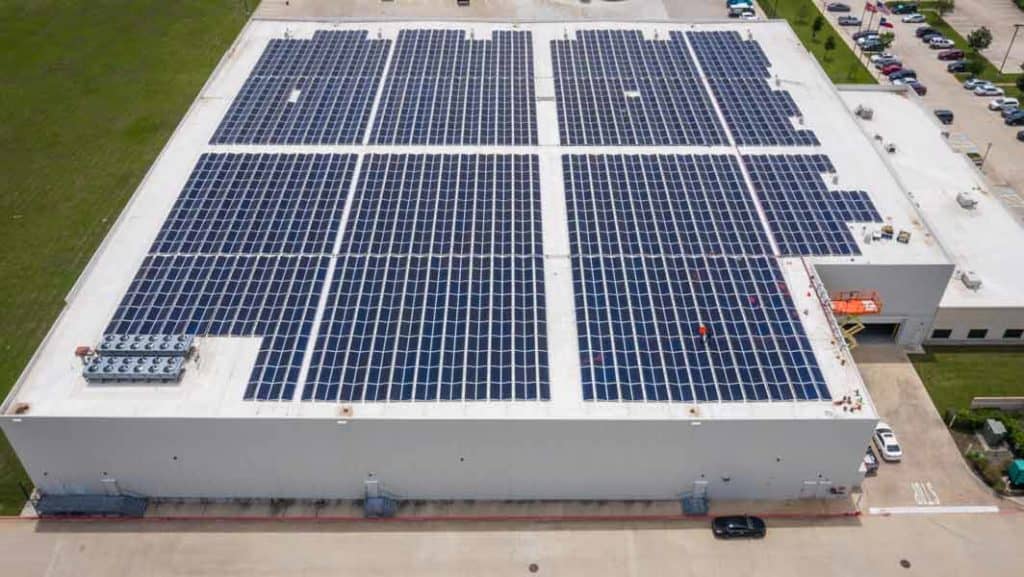 Vista lateral del techo de Ben E. Keith Company en Fort Worth, Texas, con un conjunto de paneles solares instalado en el techo y automóviles estacionados