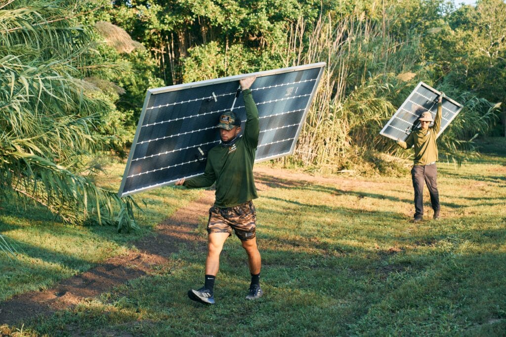 Arbeiter tragen Sonnenkollektoren durch die Wildnis der King Ranch