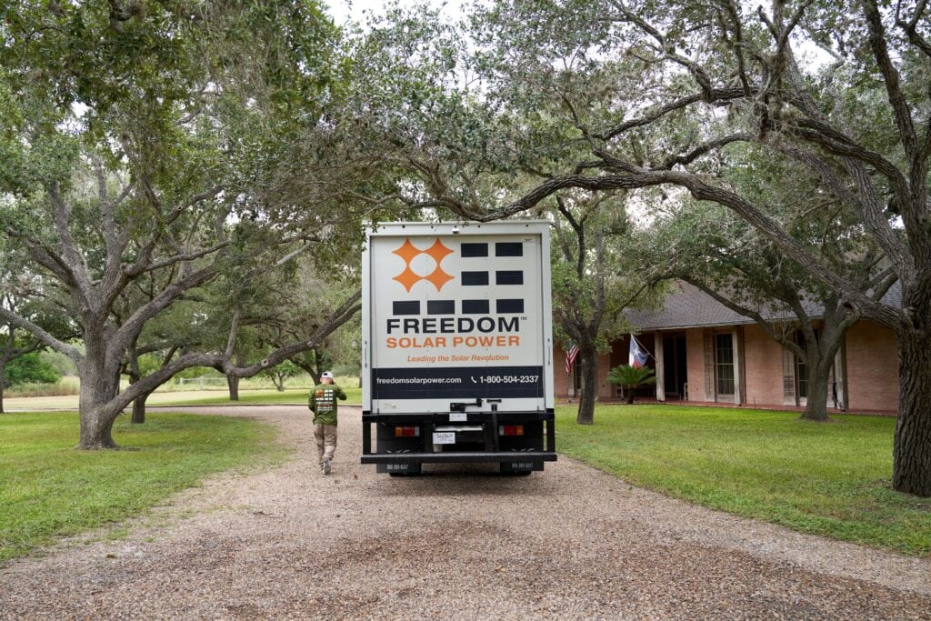 White-Box-Truck fährt auf Schotterstraße unter texanischen Mesquite-Bäumen