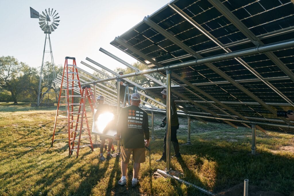 4-köpfiges Arbeitsteam transportiert Solarpanel zum Bodenmontageregalsystem