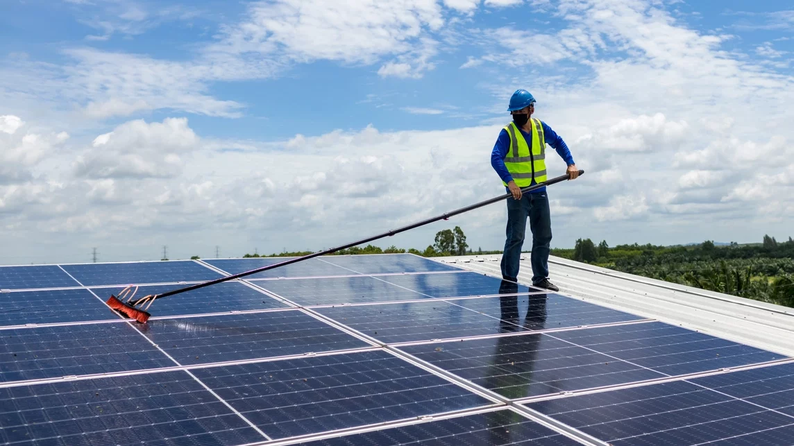 Trabajador en el techo limpia paneles solares