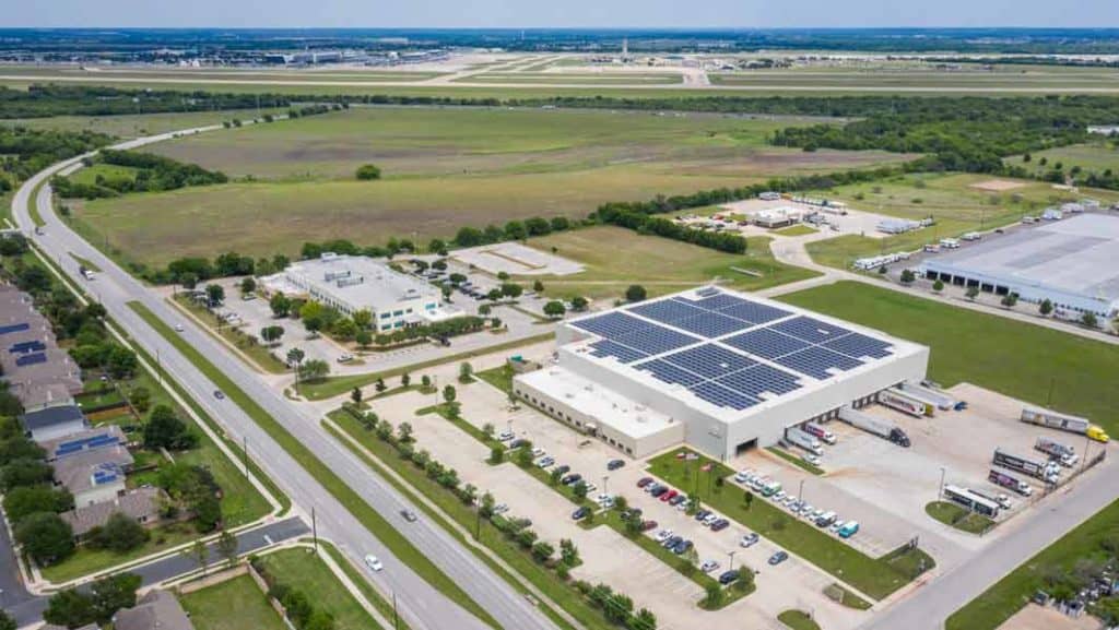 Vista por drones del edificio de Ben E. Keith Company en Fort Worth, Texas, con una hilera de paneles solares en el techo y vegetación a su alrededor.