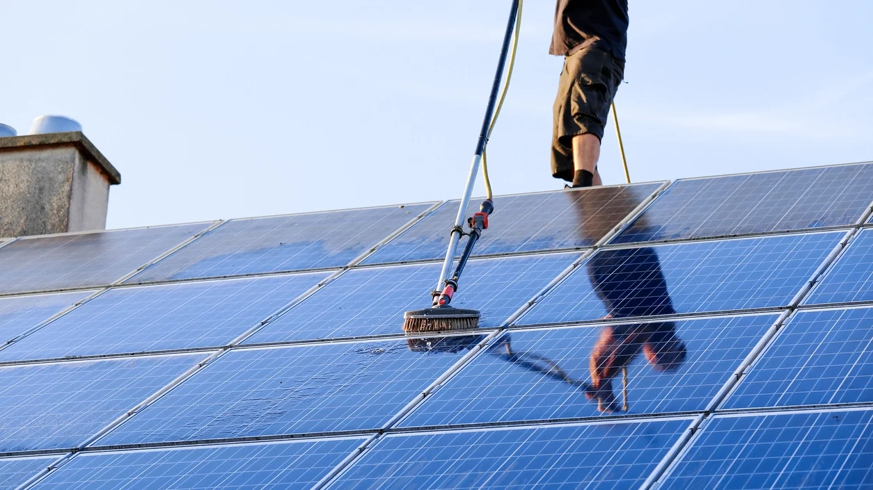 Mann reinigt ein Solarpanel auf dem Dach