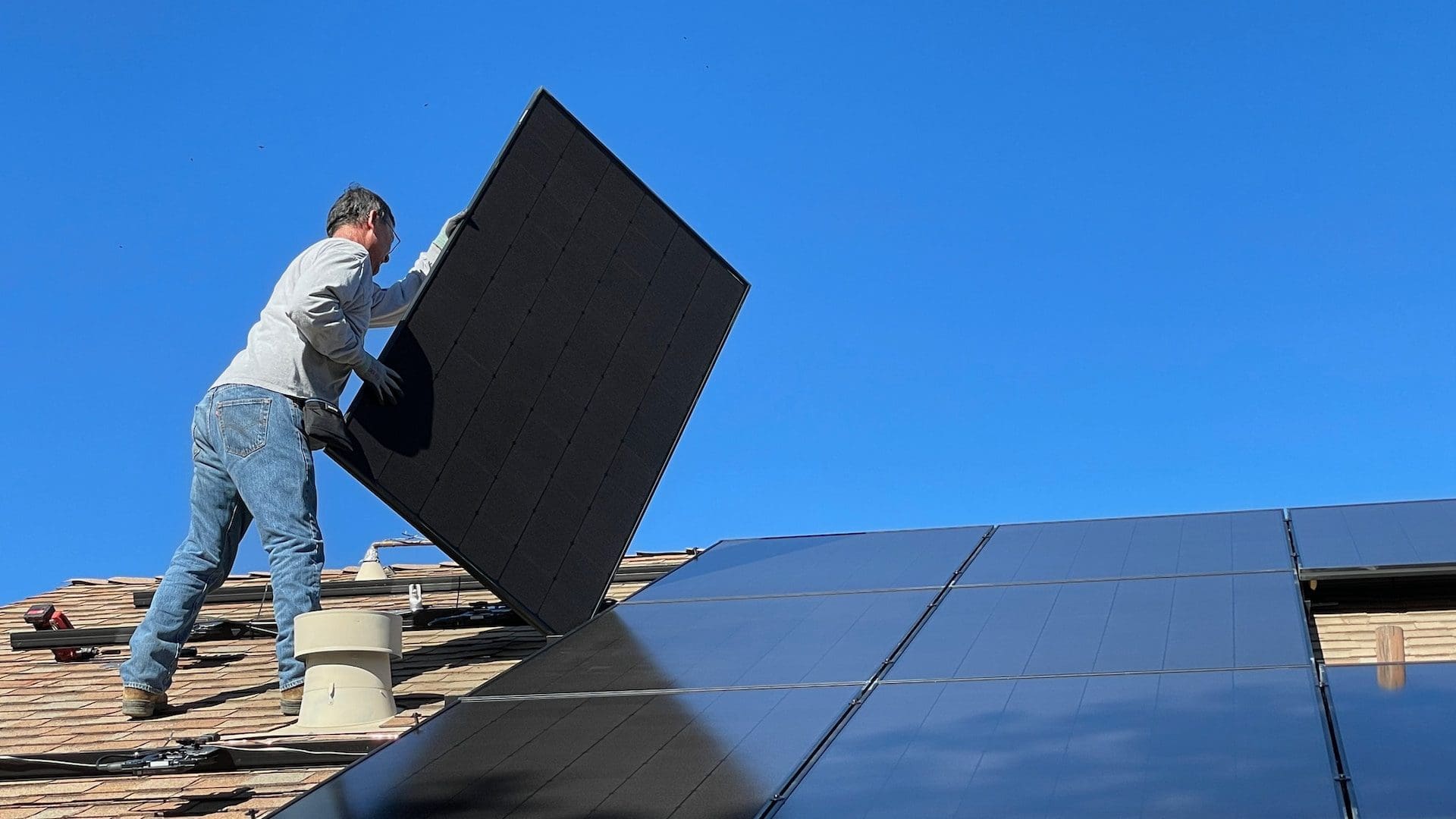 Hombre instalando paneles solares en el techo en un día soleado