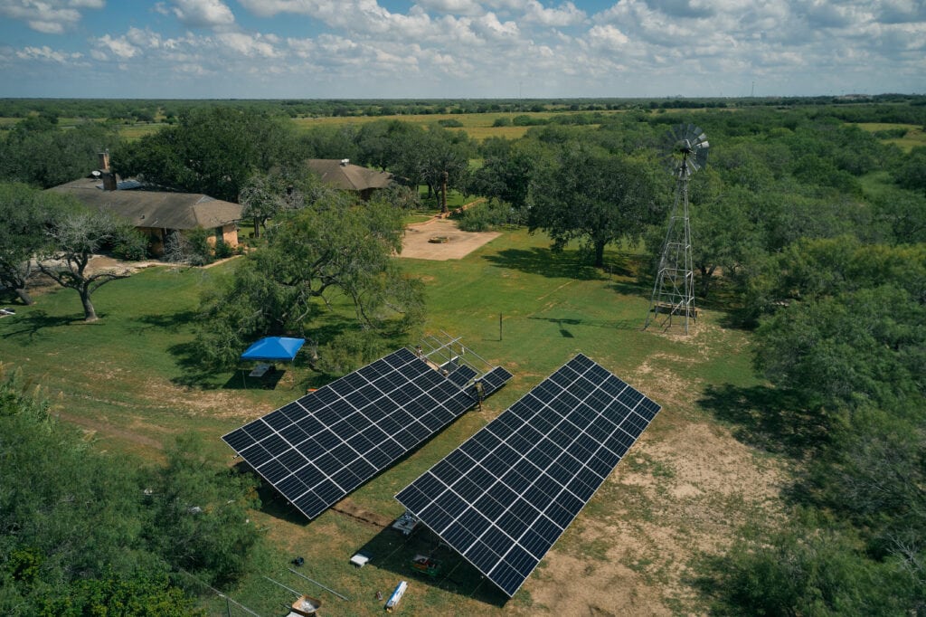 Luftaufnahme eines Ranchhauses, Mesquite-Bäumen im Süden von Texas und bodenmontierten Sonnenkollektoren