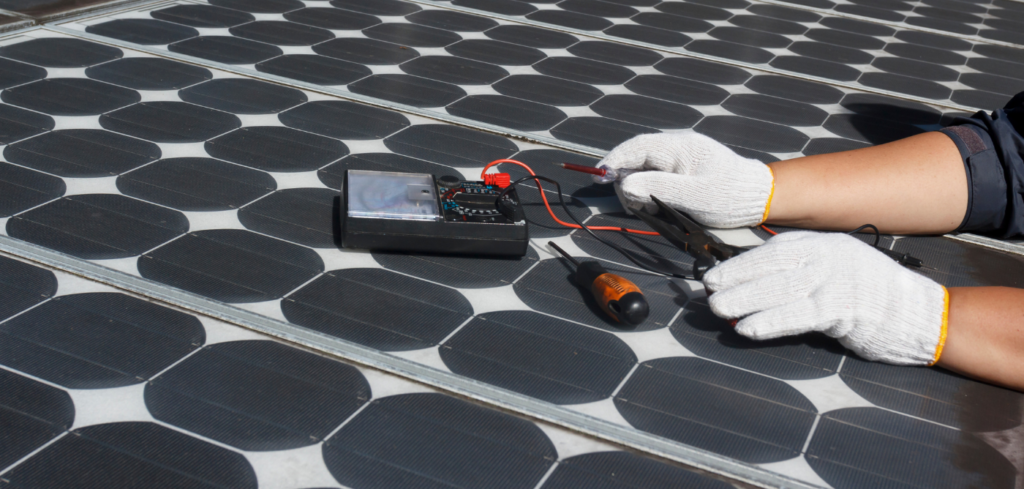 Solarni tehničar s bijelim rukavicama pregledava fotonaponske solarne panele multimetrom.