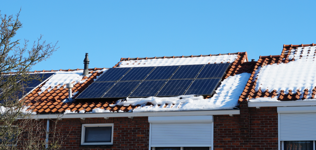 Skup solarnih panela na krovu kuće, ali su prekriveni slojem snijega.